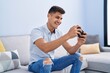 © Krakenimages.com - Young hispanic man playing video game sitting on sofa at home