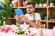 © Krakenimages.com - Young hispanic man florist smiling confident using touchpad at flower shop