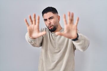 Poster - Young handsome man standing over isolated background afraid and terrified with fear expression stop gesture with hands, shouting in shock. panic concept.