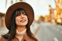 Brunette Woman Wearing Winter Hat Smiling Outdoors At The City On Sunset