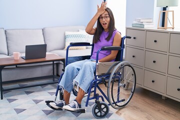 Poster - Young hispanic woman sitting on wheelchair at home surprised with hand on head for mistake, remember error. forgot, bad memory concept.