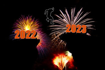 man  jumping over a cliff, skipping 2022 into 2023 on the fireworks background,  happy New year concept.