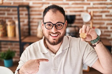 Wall Mural - Plus size hispanic man with beard holding virtual currency bitcoin pointing finger to one self smiling happy and proud