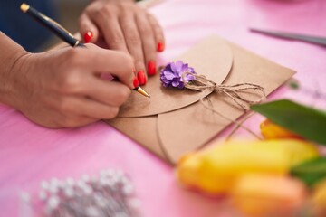 Poster - Young blonde woman florist writting on envelope letter at florist store