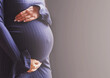 pregnant woman's belly closeup. hands hugging belly in blue background. Concept of maternal health