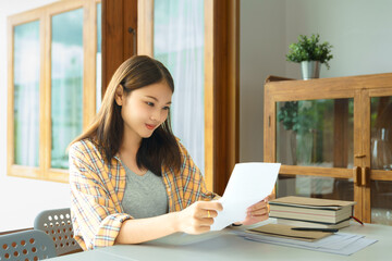 Wall Mural - Education and literacy concept, College student girl is reading lesson sheet in college library