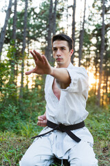 A young man doing karate in the forest training strength pose meditation 