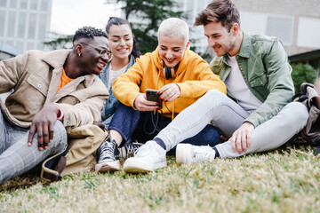 Wall Mural - Happy University student friends having fun sharing moments on smartphone app sitting on the campus grass