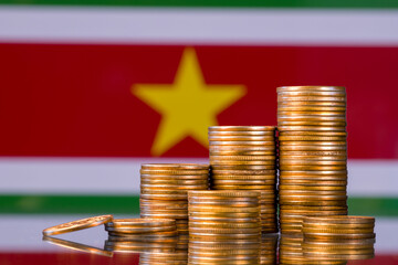 A stack of gold coins on the background of the flag of 
Suriname. Country economy concept