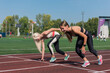 © olinchuk - Two athlete young woman runnner on the start at the stadium outdoors