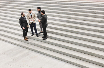 Poster - Business people outdoor meeting. A group of men in suits stands against the backdrop of the urban steps of a large staircase. Working break. Teamwork and career advancement. Successful promotion