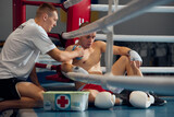 Fototapeta  - Personal coach, team trainer helping male boxer to relax hand, avoid injuries during the boxing training in the gym