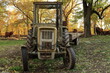 © jarizPJ - An old yellow tractor standing on a farm with a background of autumn leaves.Stary żółty traktor stojący na farmie na tle jesiennych liści