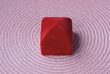 one small closed red ring box stands on a pink table