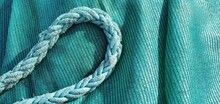 Marine Rope And Fishing Net. Blue Rope. Turquoise Background. Turquoise Fishing Net And Rope. Fishing Gear. Blue Cord On A Blue Background.