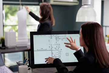 Real estate agent drafting in room floor planner software, zooming in apartment plan with touchscreen. Cad, blueprints on computer monitor screen, designer working in architecture office