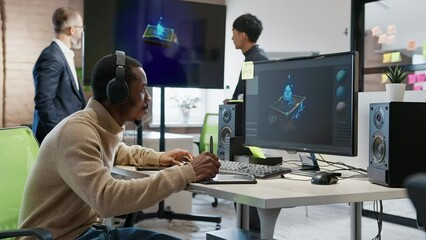 African American male artist designer draws on a tablet a 3D model for a computer game in the office of a project development studio.