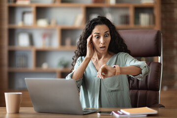 Wall Mural - Stressed young businesswoman looking at watch, got late