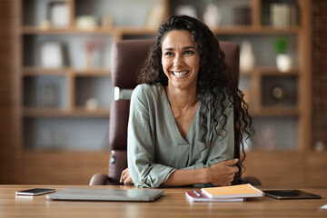 Wall Mural - Cheerful young woman posing at workdesk at office, copy space