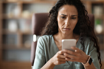 Wall Mural - Closeup of confused woman looking at cell phone screen