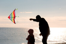 Father And Daughter Flying A Kite Having Fun At The Beach