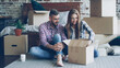 © silverkblack - Excited young couple is unpacking things, opening box, taking personal items and talking after moving to new apartment. Relationship, emotions and relocation concept.