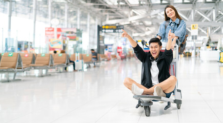 Wall Mural - Happy smiling asian male and female waiting for flight and Check-in by mobile phone in terminal background.asian couple are traveling after the coronavirus 2019 (COVID-19) outbreak ends.