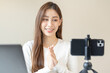 © KMPZZZ - Vlogger influencer, attractive asian young woman blogger, content maker looking at camera, recording interview on smartphone, talk on video shoot social media, live broadcast with technology at home.