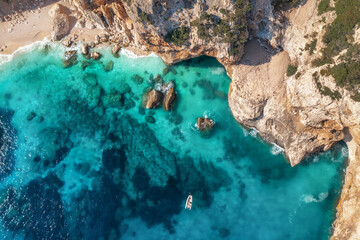 Canvas Print - Beautiful summer seascape from air. Turquoise sea water, rocks, boat and small sandy beach from top view, Island of sardinia in Italy. Travel background, aerial view drone shot