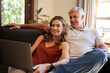 © N Lawrenson/peopleimages.com - Laptop, couple and retirement with a man and woman streaming an online subscription service on the sofa to relax. Computer, living room and internet with an elderly male and female watching a video