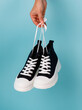 Stylish and fashionable model of black and white sneakers on blue background.
