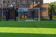 Soccer sports field with green synthetic artificial grass and gate in courtyard of residential area.