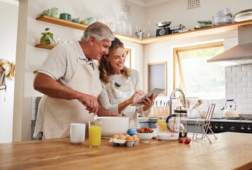 Wall Mural - Cooking, recipe and senior couple with tablet for online video for breakfast food in the kitchen of their house. Happy elderly man and woman reading on the internet with tech for healthy lunch
