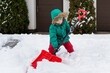Winter kids fun outdoor sports. Girl clearing sidewalks and shoveling snow. Child removaling snow with  shovel. Little helper for parents.