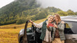 Two happy adult women senior mother and daughter traveling together by car taking selfie standing next to the car