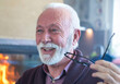 © Solid photos - Senior man taking off eyeglasses while sitting in front of fireplace in winter