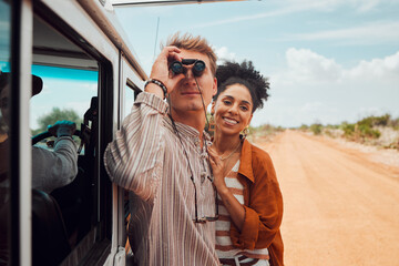 Wall Mural - Road trip, travel and view with a couple using binoculars for sightseeing while outdoor on sand road during their summer vacation. Diversity, love and holiday with a man and woman traveling on a trip