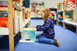 4 year old girl sitting on the floor in municipal library and reading a book