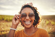 Happy, freedom and black woman with smile on a safari during a holiday in Africa. Face portrait of an African girl with sunglasses in summer during travel in nature for vacation or adventure