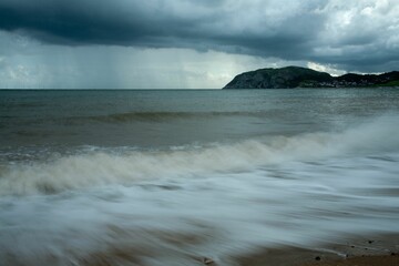 Stormy clouds in the sky and sea waves at Llandudno beach in North Wales