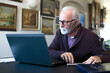 © Solid photos - Senior man online shopping and working on laptop at home