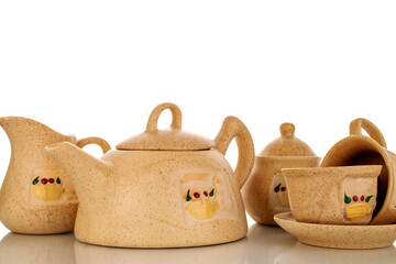 Poster - Two clay cups on a saucer, a milk jug, a teapot and a sugar bowl, macro, isolated on a white background.