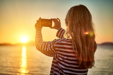 Woman traveler tourist using smartphone, taking photo of sea view at sunset in summer day. Enjoying European, Famous popular touristic place in world.
