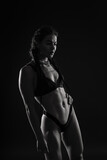 Fototapeta  - Close-up shot of young woman waist with muscular abdominal muscles. Abs of fit female athlete.