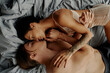 © LIGHTFIELD STUDIOS - Top view of young brunette couple kissing while lying on bed.