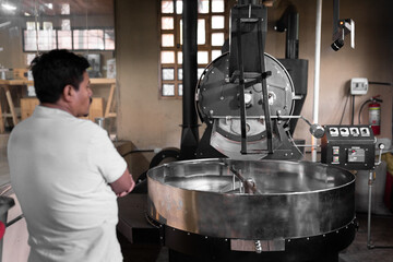 An Hispanic man is waiting for the coffee roster machine to finish