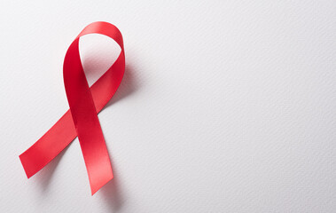 Closeup red ribbon HIV, world AIDS day awareness ribbon on white background. Healthcare and medicine concept.