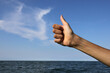 © ChiccoDodiFC - hand with thumb raised as a sign of success and the sea with the sky