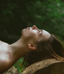 Canvas Print - Side profile of a Caucasian woman laying over tree trunk, looking up, nature scene.