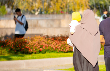 Wall Mural - Muslim family spend time together in the park. Girl in a hijab. Romantic Muslim couple in love with a baby in their arms.